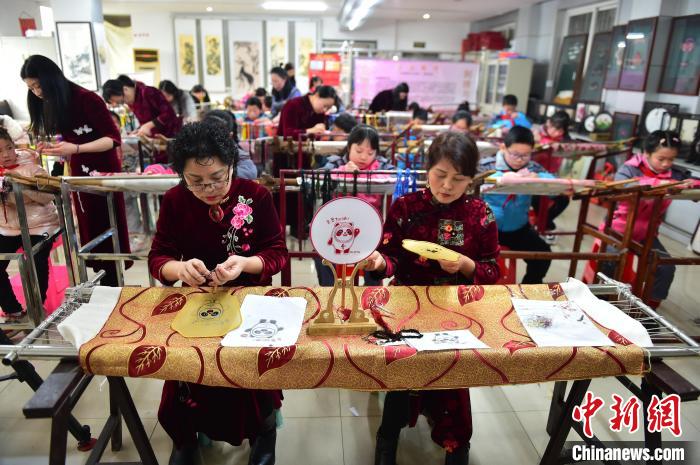 江西省級非遺豫章繡傳承人手把手指導(dǎo)小學(xué)生繡制2022年北京冬奧會吉祥物“冰墩墩”形象。　喻云亮 攝