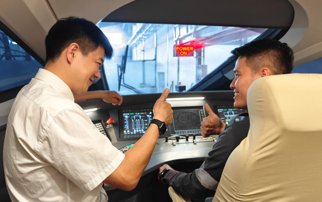 8月25日，在印度尼西亞萬隆的雅萬高鐵德卡魯爾動車所內(nèi)，中國師傅穆振（左）在向印尼火車司機塞蒂亞萬講解動車組出庫前的上電作業(yè)。