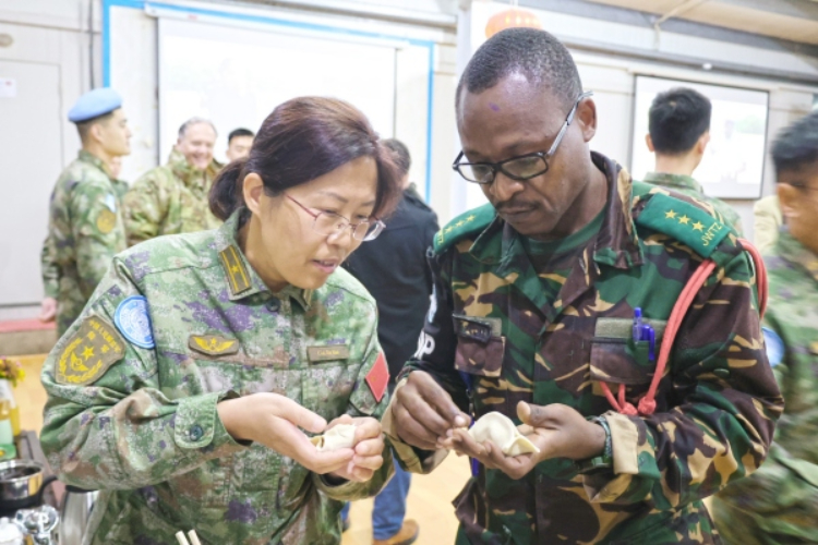 圖為維和官兵與外軍人員共同包餃子。胡光明攝