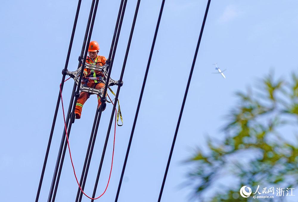 3月11日，在浙江省諸暨市河上鎮(zhèn)，浙江省送變電工程有限公司檢修人員在高空的導線上進行線路檢修維護。人民網(wǎng) 章勇濤攝
