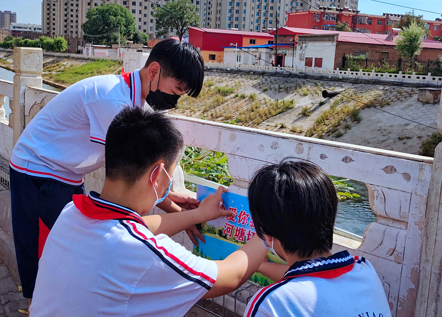 徐水小學(xué)學(xué)雷鋒志愿者在瀑河河邊張貼防溺水警示標(biāo)語(yǔ)。 徐水區(qū)委宣傳部供圖