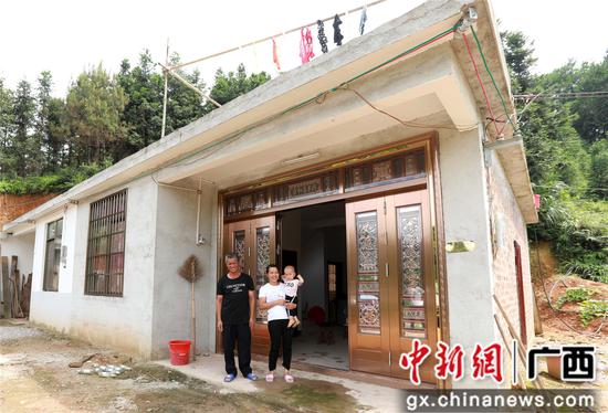 7月4日，在廣西柳州市融安縣大坡鄉(xiāng)崗偉村，脫貧戶肖裕安（左）與妻子、外孫在改造后的房屋前合影。覃慶和 攝