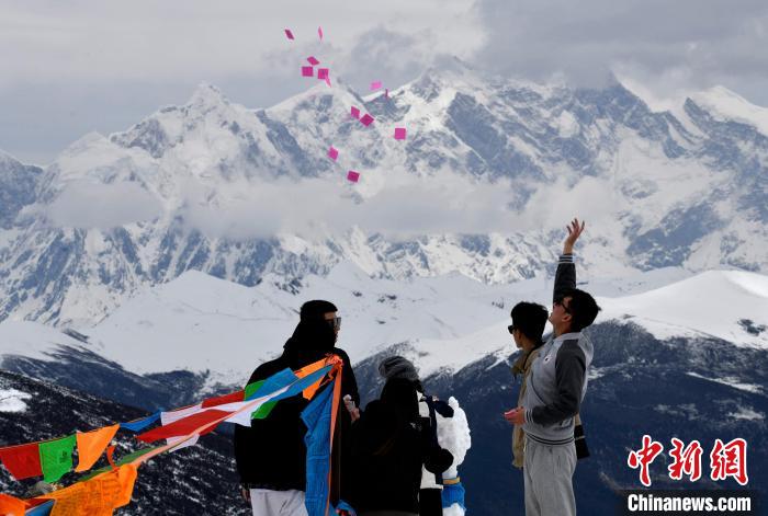 圖為5月14日，游客在西藏林芝色季拉山觀景臺拋灑“隆達”(風馬旗，藏族民眾的一種祈福方式)。　李林 攝
