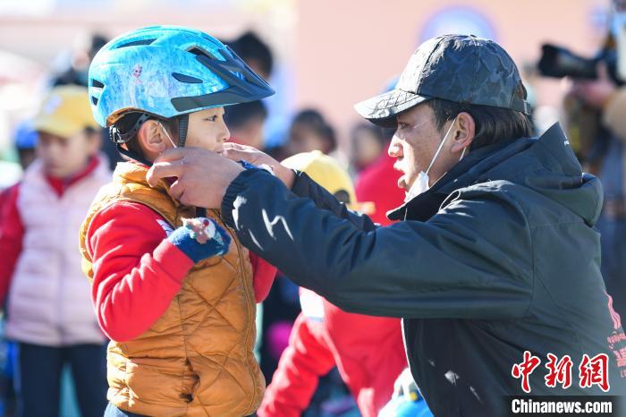 圖為拉薩市實(shí)驗(yàn)幼兒園孩子在教練的幫助下穿戴頭盔。　何蓬磊 攝