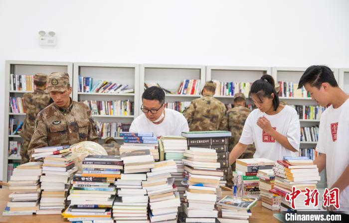 圖為志愿者們和邊防戰(zhàn)士整理圖書(shū)?！詵| 攝