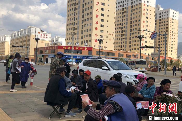 圖為會澤縣城易地扶貧搬遷安置點內，老人們聚在廣場上聊天，身后是他們的新家?！】姵?攝