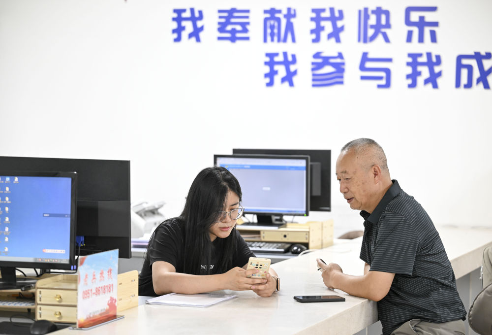 2024年6月20日，在寧夏銀川市金鳳區(qū)長城花園社區(qū)黨群服務中心，工作人員幫助居民辦理業(yè)務。圖片來源 新華社