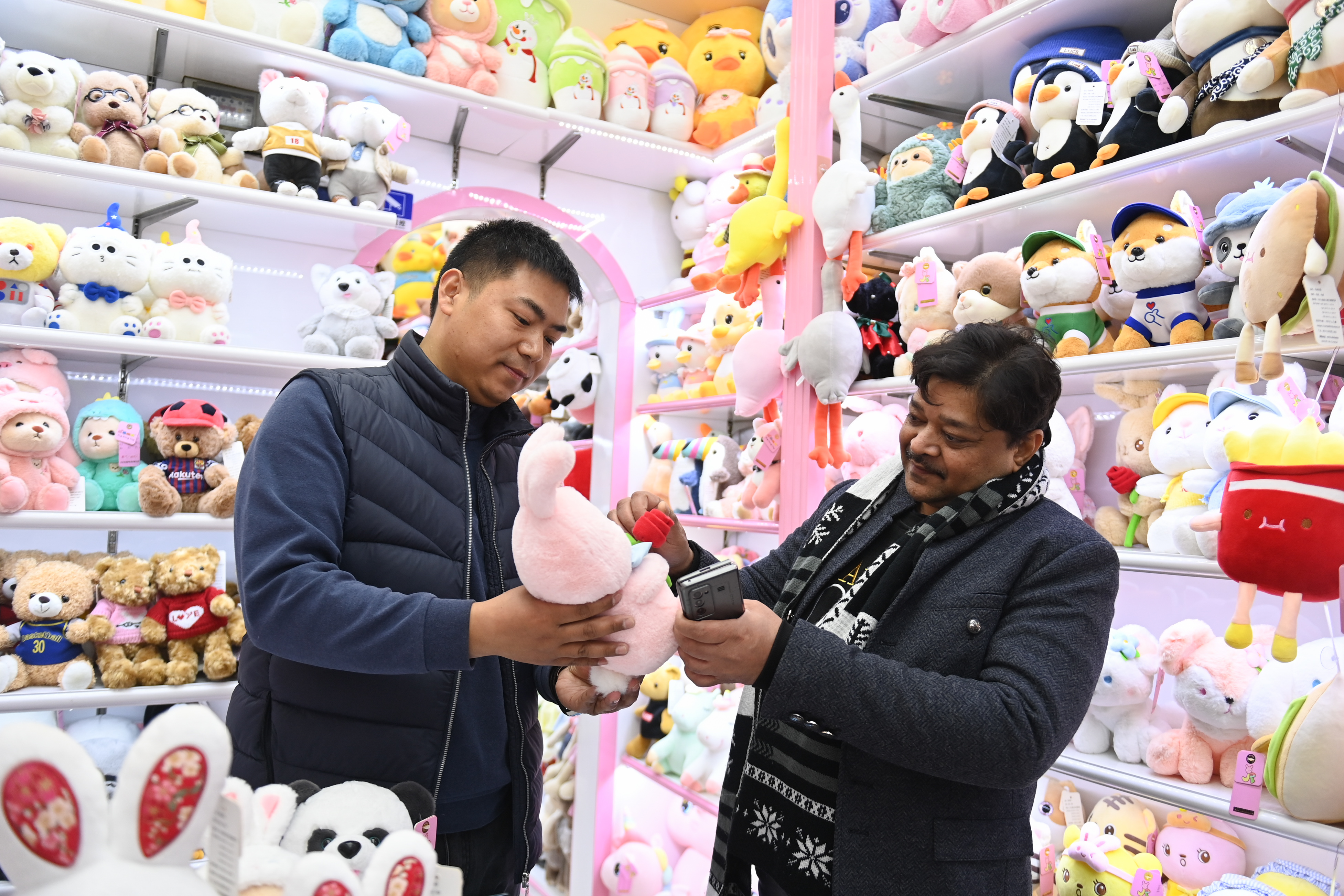 2023年2月2日，來自印度的客商（右）在義烏國際商貿(mào)城的一家玩具店鋪內(nèi)選購。