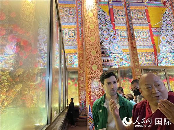7月25日，省級非物質(zhì)文化遺產(chǎn)項(xiàng)目塔爾寺酥油花的代表性傳承人朋措堅(jiān)參（右）在塔爾寺酥油花館講解酥油花的制作過程。人民網(wǎng) 謝瑩攝