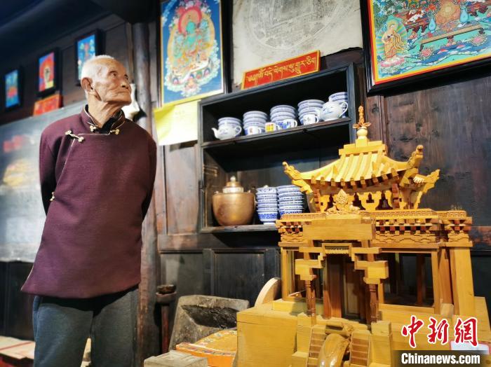 圖為古堡內(nèi)的藝人桑杰展示自己的雕刻作品?！?zhí)砀?攝