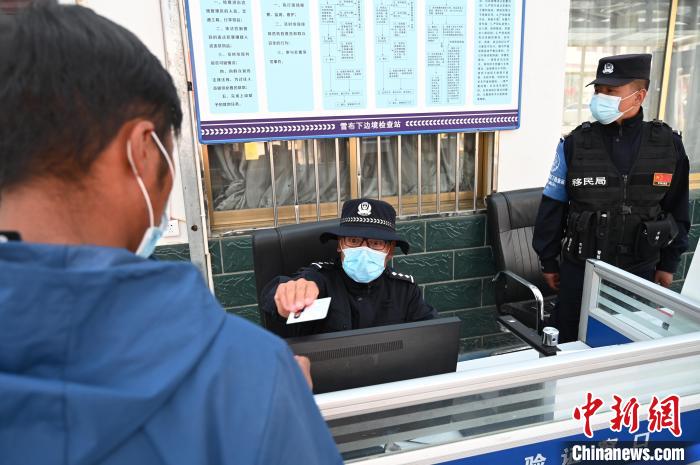 圖為移民管理警察登記完身份信息后將證件歸還給行人?！≮w朗 攝