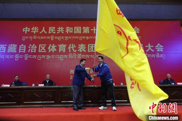 西藏自治區(qū)副主席甲熱·洛桑丹增授代表團團旗，西藏自治區(qū)體育局局長尼瑪次仁接旗?！∪轿木?攝
