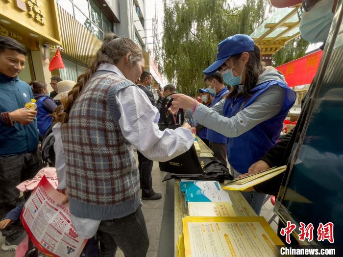 圖為志愿者為市民發(fā)放網(wǎng)絡(luò)安全宣傳手冊。　謝牧 攝