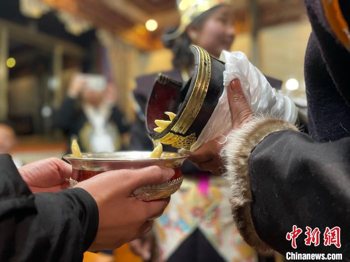 圖為主人在碗中斟滿青稞酒。　冉文娟 攝