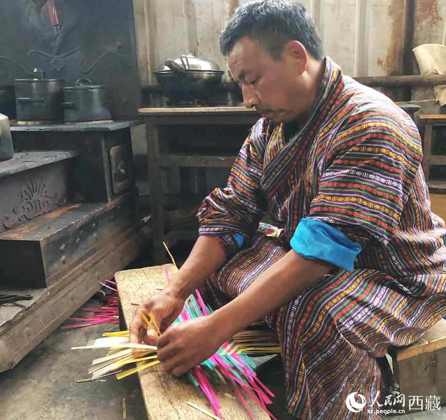 門巴族漢子愛明正在編織藤竹品。